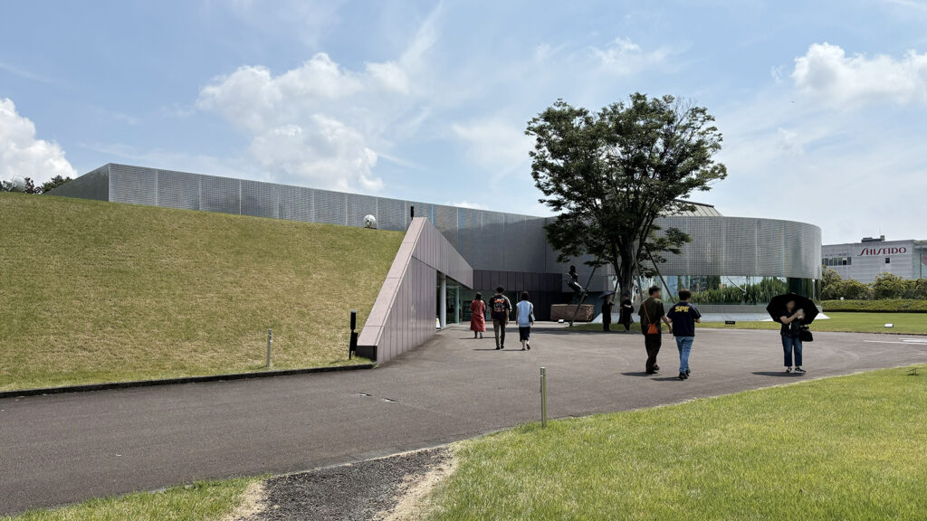 資生堂アートハウス 外観。緑の多くない地域に建っていることもあり、敷地は公園のような存在感。右手奥に見えるのは資生堂の掛川工場