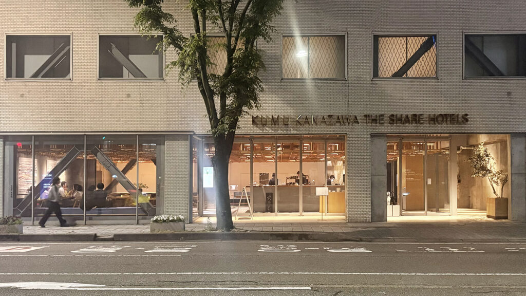 KUMU金沢 夜の外観。全面ガラス張りの開放的な設えのために内部の木格子の姿が透けて見える